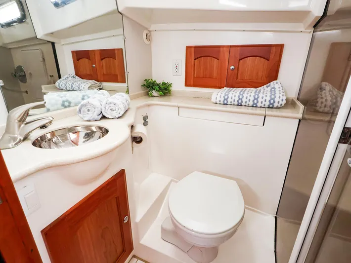 4814ak Yacht Photos Pics Compact boat bathroom with sink, toilet, and wooden cabinets in a 2009 Legacy 32 model.