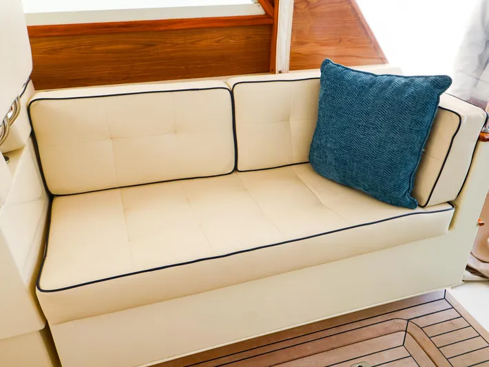 4814ak Yacht Photos Pics Cream sofa with blue cushion on Legacy 32, 2009 model, featuring wooden accents.