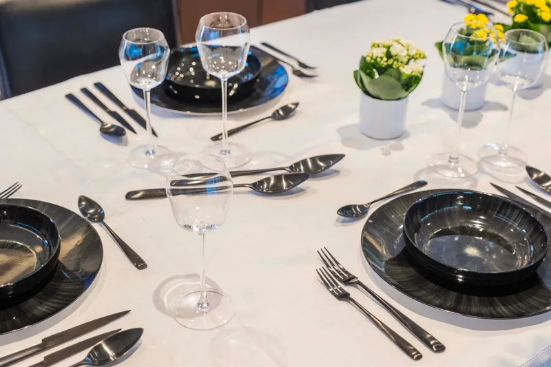 Bellini Yacht Photos Pics Elegant dining setup on Cantieri di Pisa AKHIR 30 yacht, featuring black plates and wine glasses.
