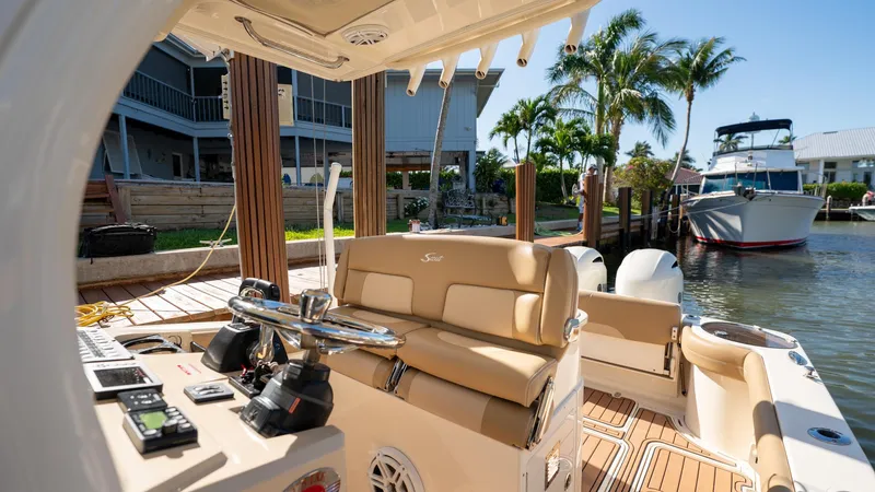  Yacht Photos Pics 2019 Scout 275 LXF boat interior with helm, docked near waterfront homes and palm trees.