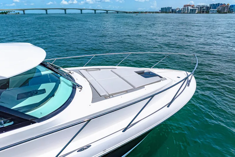  Yacht Photos Pics 2022 Tiara Yachts 43 LE cruising on blue water near a bridge and cityscape.