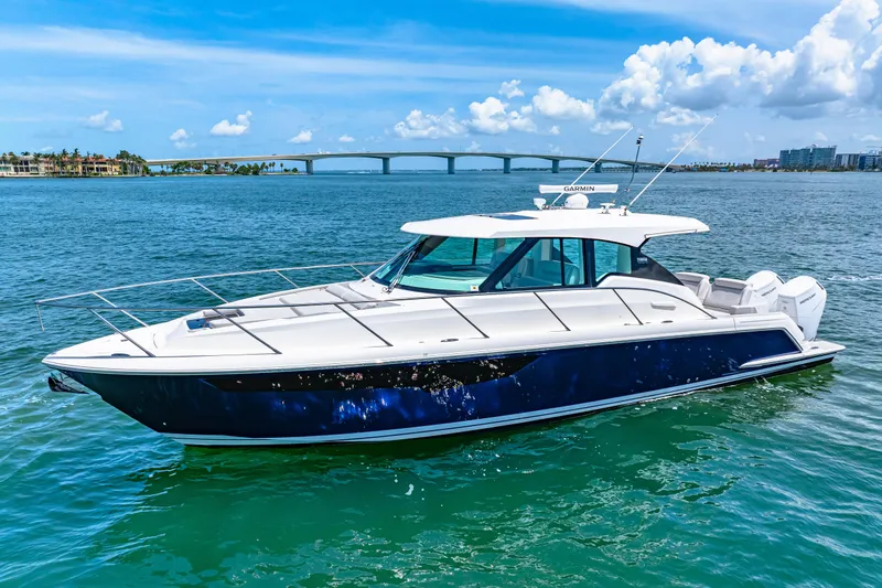  Yacht Photos Pics 2022 Tiara Yachts 43 LE cruising on clear blue water with a scenic bridge backdrop.