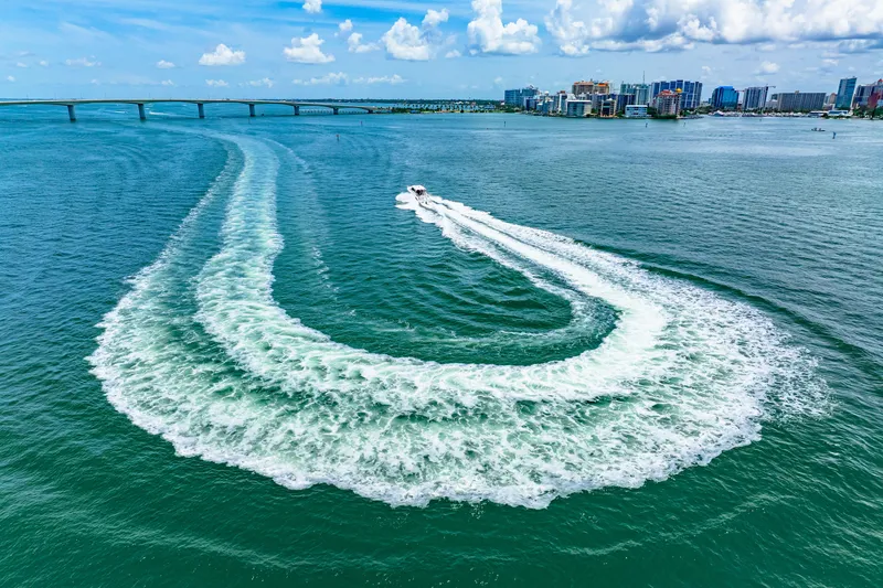  Yacht Photos Pics 2022 Tiara Yachts 43 LE creating a wake in open water near a cityscape.