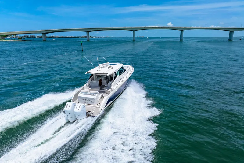  Yacht Photos Pics 2022 Tiara Yachts 43 LE cruising under a bridge on a sunny day.