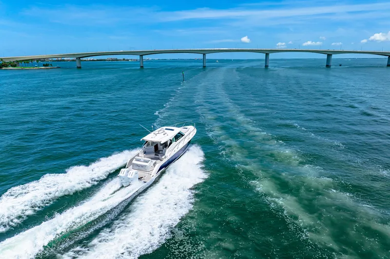  Yacht Photos Pics 2022 Tiara Yachts 43 LE cruising under a bridge on a sunny day.
