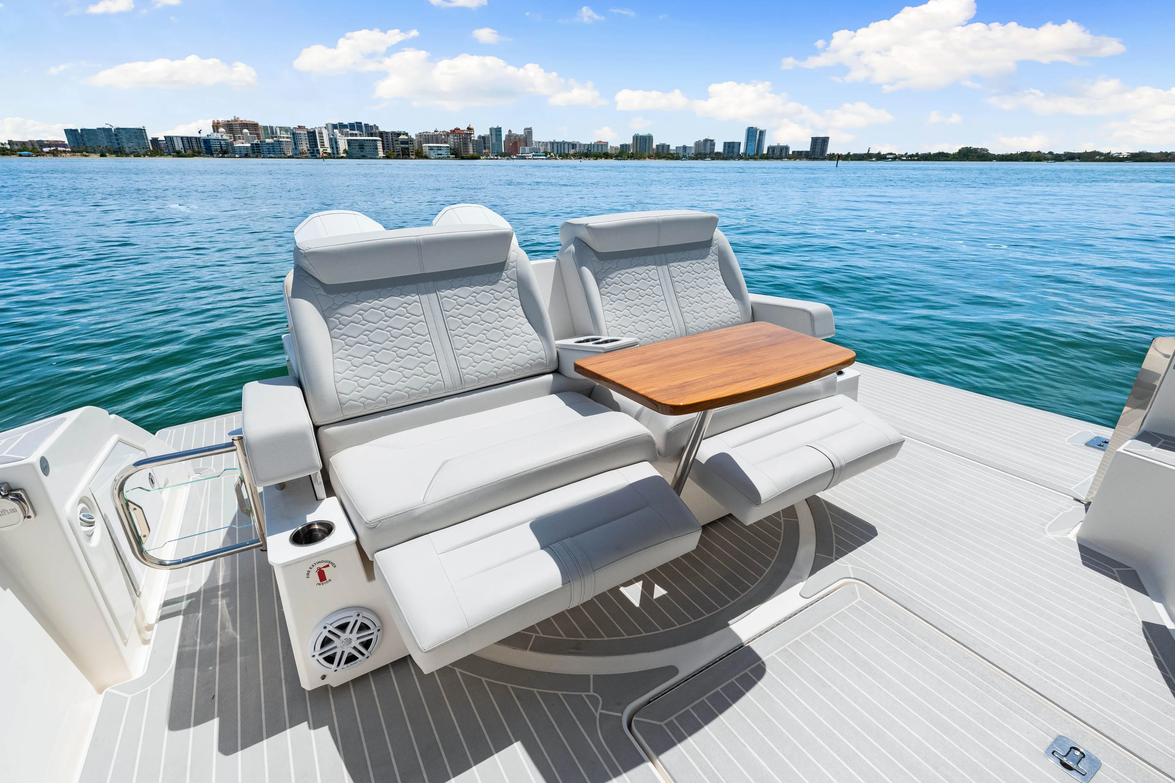 Yacht Photos Pics 2022 Tiara Yachts 43 LE luxury seating with table, overlooking serene waterfront cityscape.