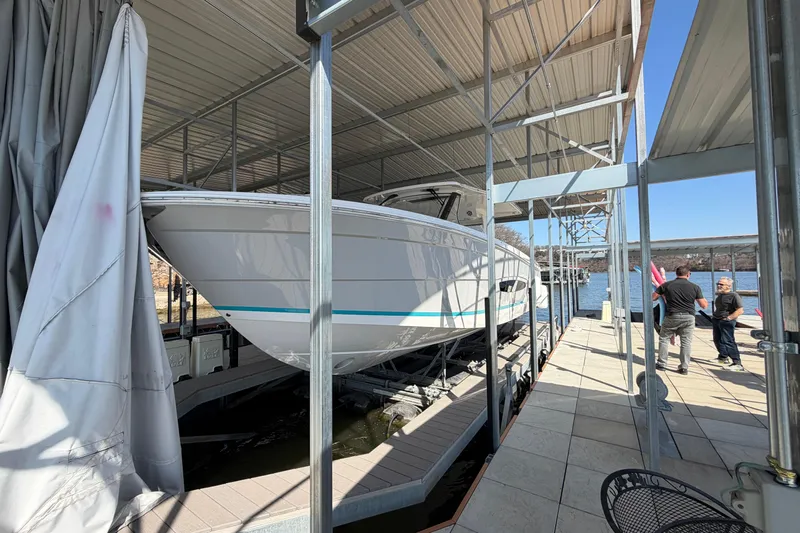  Yacht Photos Pics 2023 Regal 38 SAV boat docked under a metal canopy by the water.