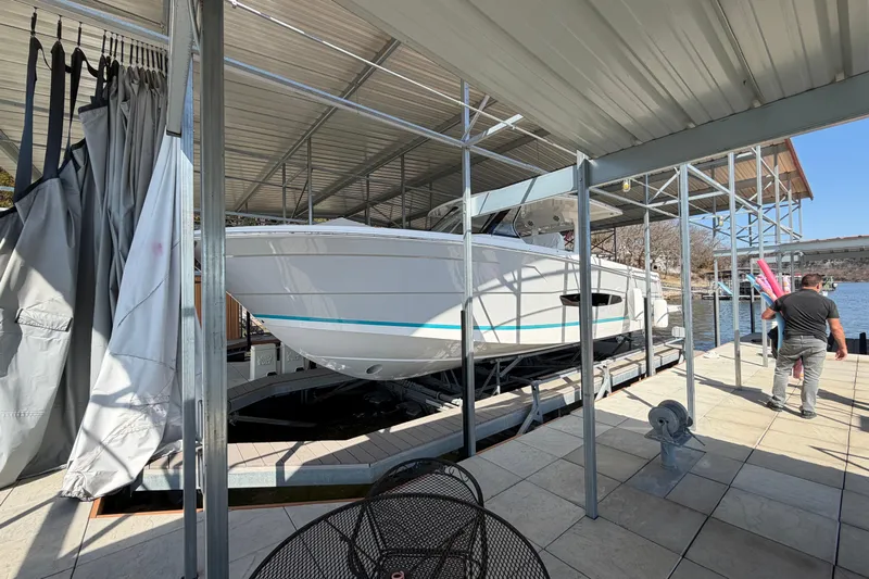  Yacht Photos Pics 2023 Regal 38 SAV boat docked under a metal canopy by the water.