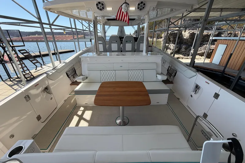  Yacht Photos Pics 2023 Regal 38 SAV boat interior with seating and wooden table, docked by the water.