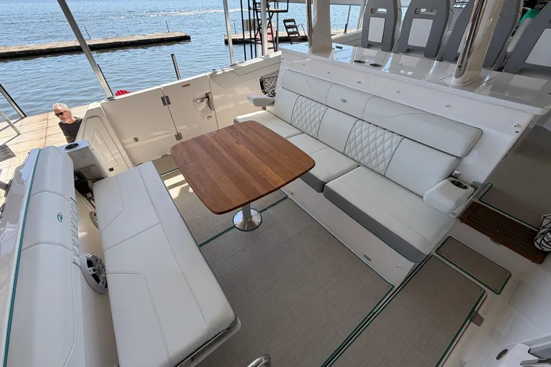  Yacht Photos Pics Luxurious seating area on 2023 Regal 38 SAV boat with wooden table and waterfront view.
