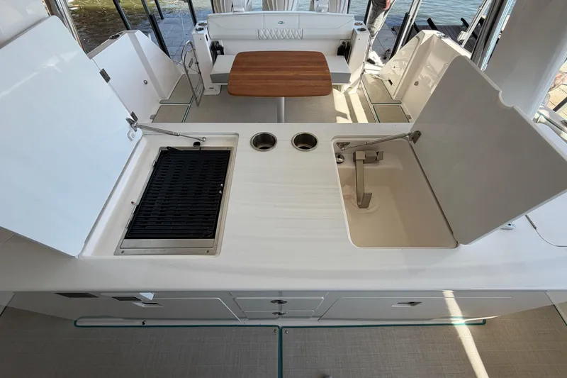  Yacht Photos Pics 2023 Regal 38 SAV boat interior with grill, sink, and wooden table.
