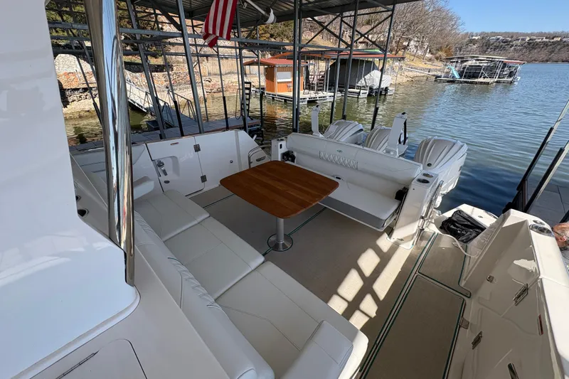  Yacht Photos Pics 2023 Regal 38 SAV boat interior with seating and table, docked by a serene lake.