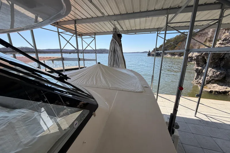  Yacht Photos Pics 2023 Regal 38 SAV boat docked under a covered structure by a scenic lake.