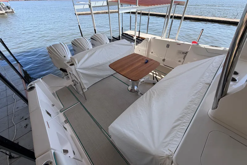  Yacht Photos Pics 2023 Regal 38 SAV boat interior with covered seating and wooden table by the water.