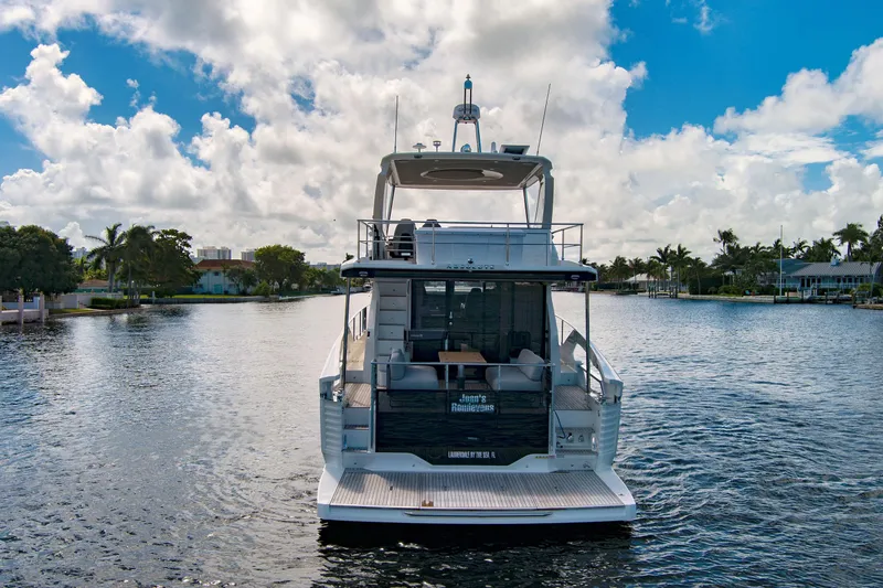 Joan's Rondevous Yacht Photos Pics 2025 Absolute 52 FLY yacht on a serene waterway under a partly cloudy sky.