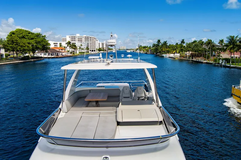 Joan's Rondevous Yacht Photos Pics Luxurious 2025 Absolute 52 FLY yacht cruising on a scenic waterway with palm trees.