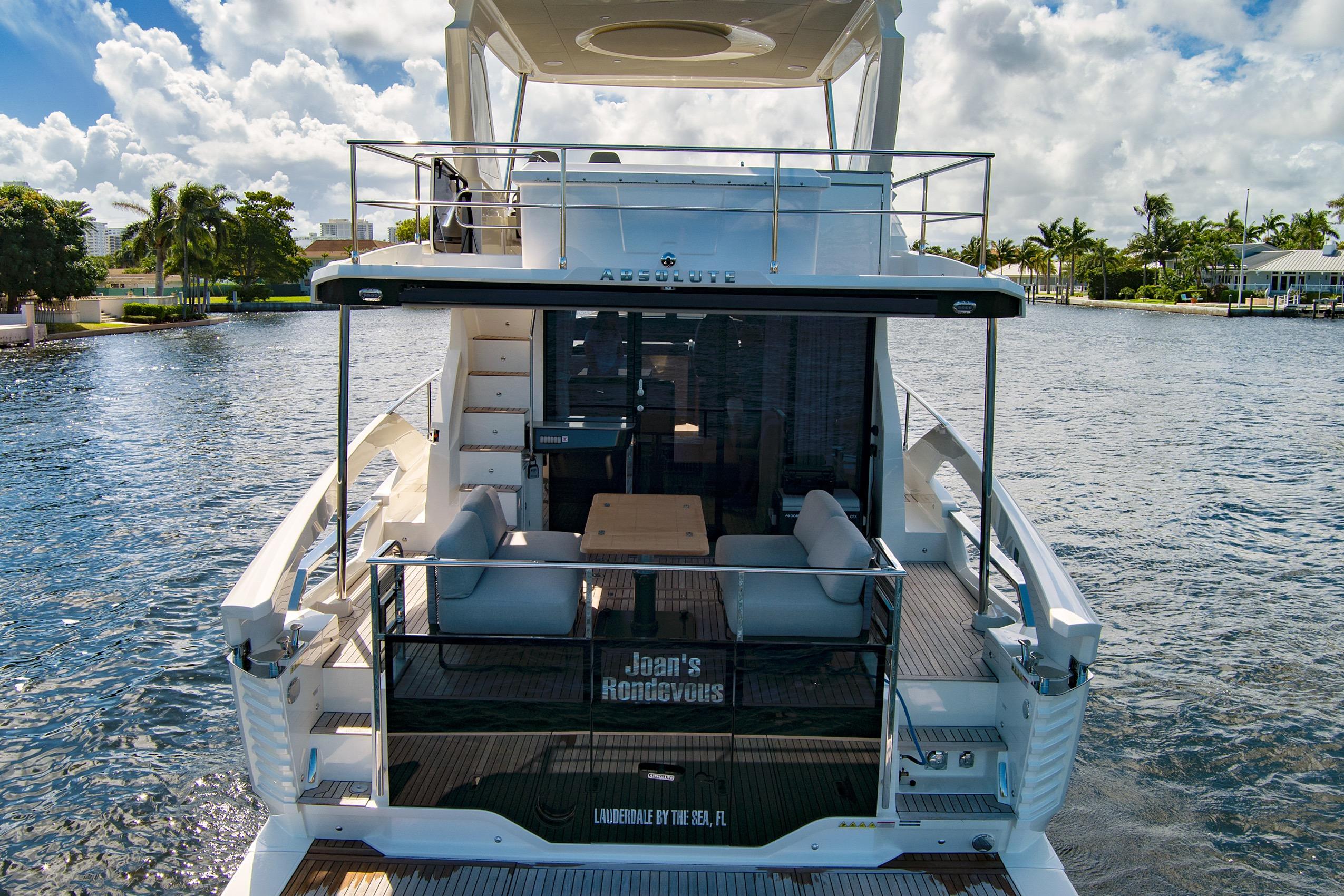 2025 Absolute 52 FLY yacht on water, featuring spacious deck and luxurious seating.