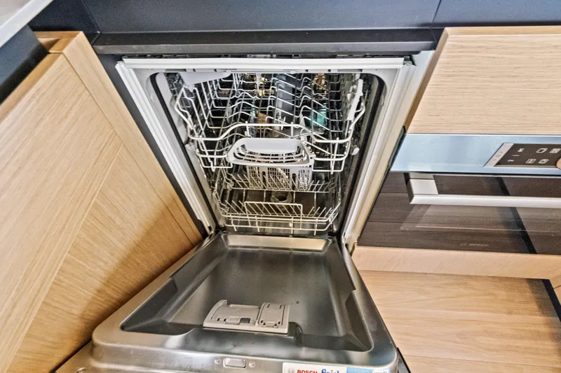 Joan's Rondevous Yacht Photos Pics Open dishwasher in Absolute 52 FLY yacht kitchen, 2025 model, with wooden cabinetry.