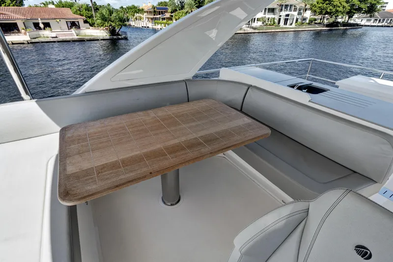 Joan's Rondevous Yacht Photos Pics Luxurious seating area on 2025 Absolute 52 FLY yacht with wooden table and waterfront view.