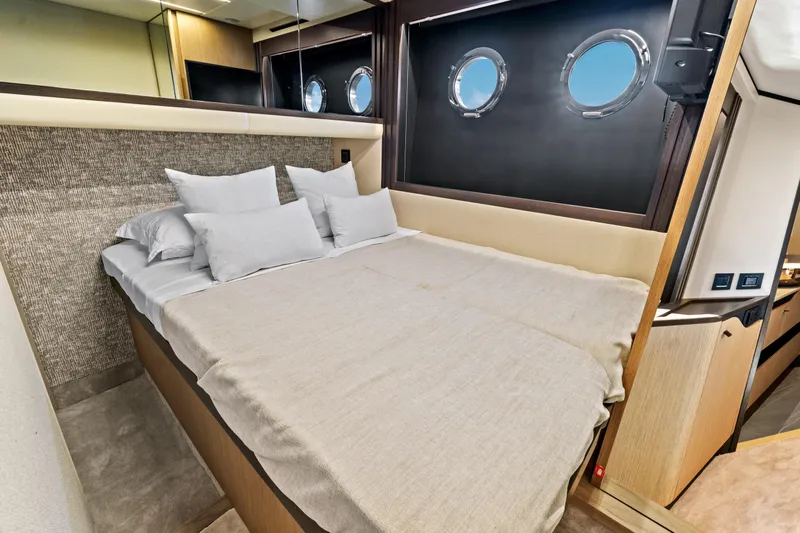 Joan's Rondevous Yacht Photos Pics Luxurious bedroom interior of 2025 Absolute 52 FLY yacht with porthole windows.