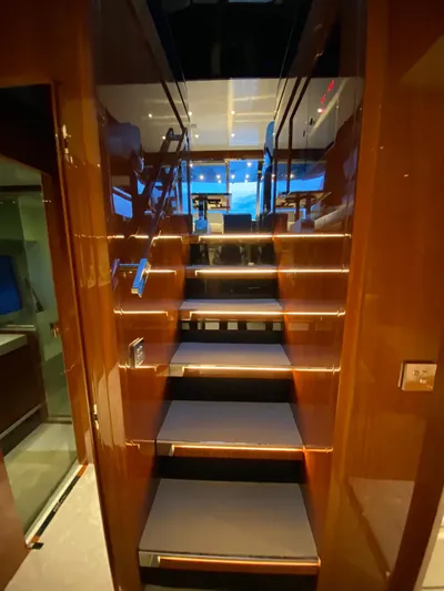  Yacht Photos Pics Interior staircase of 2020 Riva 66' Ribelle yacht, featuring sleek wooden design and ambient lighting.