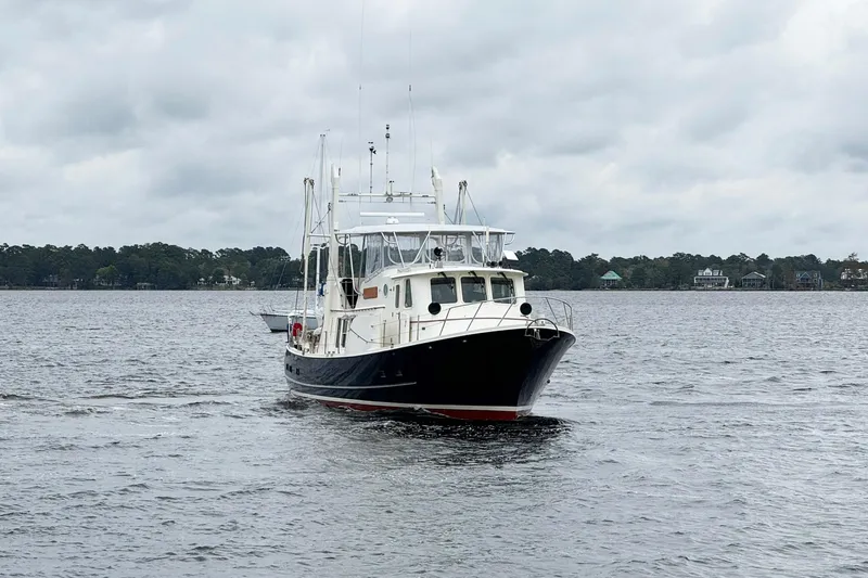  Yacht Photos Pics 1989 Seaton Trawler cruising on a calm lake under cloudy skies.