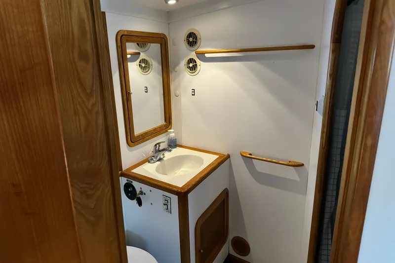  Yacht Photos Pics Compact bathroom in a 1989 Seaton Trawler, featuring a sink, mirror, and wooden accents.