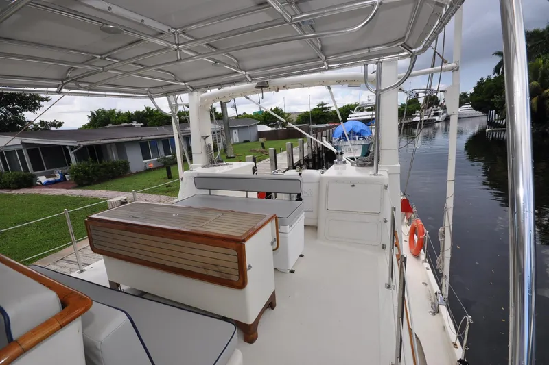  Yacht Photos Pics 1989 Seaton Trawler boat deck with seating, docked by a canal, surrounded by greenery.