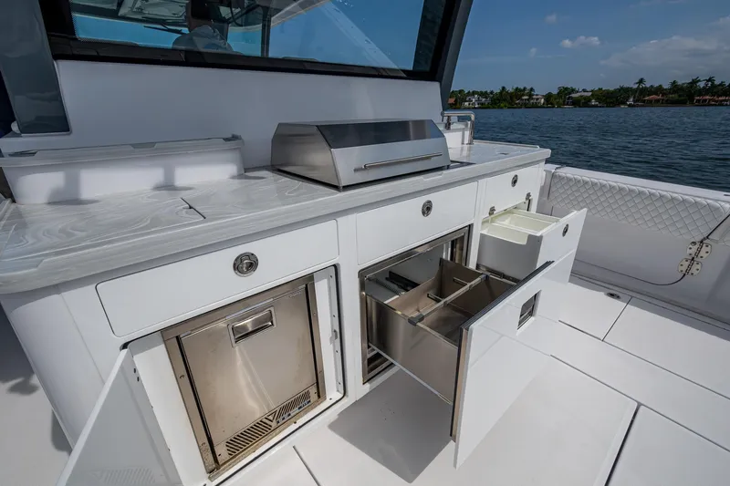  Yacht Photos Pics Outdoor kitchen on 2025 HCB 48 Campeon boat with stainless steel appliances and storage drawers.