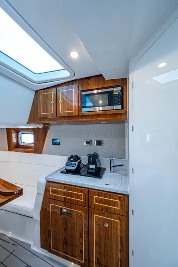  Yacht Photos Pics Interior of 2025 HCB 48 Campeon yacht with modern kitchenette and wooden cabinetry.