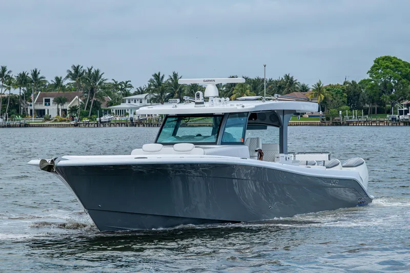  Yacht Photos Pics 2025 HCB 48 Campeon boat cruising on a calm waterway with palm trees in the background.