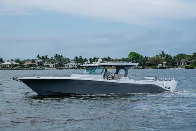  Yacht Photos Pics HCB 48 Campeon 2025 boat cruising on a calm waterway with houses in the background.