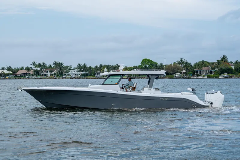  Yacht Photos Pics HCB 48 Campeon 2025 boat cruising on a calm waterway with houses in the background.