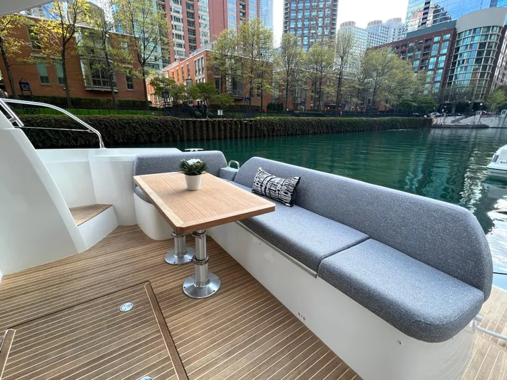  Yacht Photos Pics Luxurious 2023 Prestige 420S yacht deck with seating, table, and cityscape view.