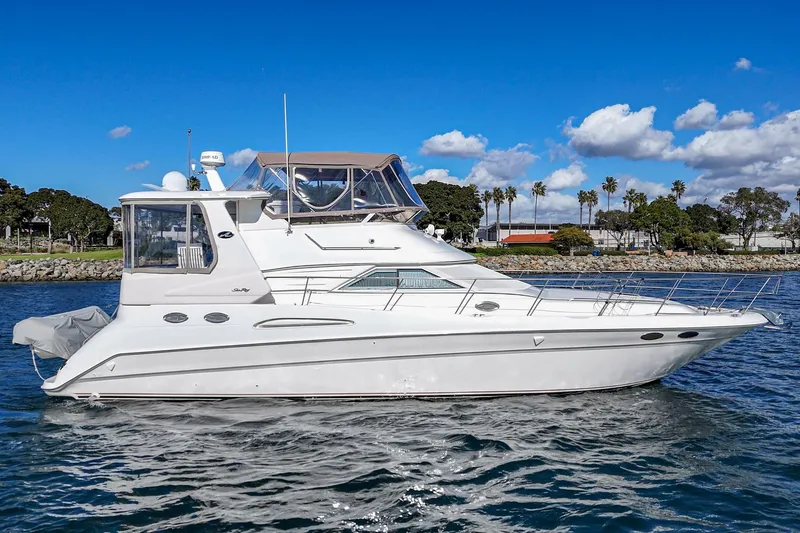 Free Spirit Yacht Photos Pics 1998 Sea Ray 420 Aft Cabin yacht on water, clear sky, palm trees in background.