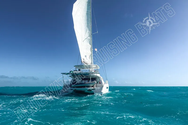 Sea Dog Yacht Photos Pics Sailing catamaran Leopard 58 cruising in turquoise ocean under clear blue sky.