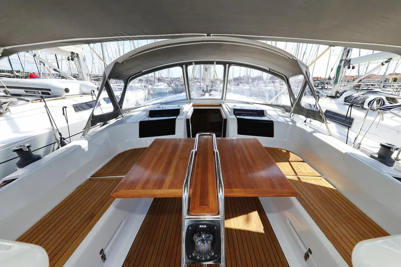 Apollo Yacht Photos Pics 2019 Hanse 458 yacht cockpit with wooden table and seating, docked in a marina.