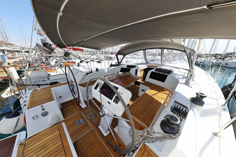 Apollo Yacht Photos Pics 2019 Hanse 458 yacht cockpit with teak flooring and dual steering wheels in a marina.