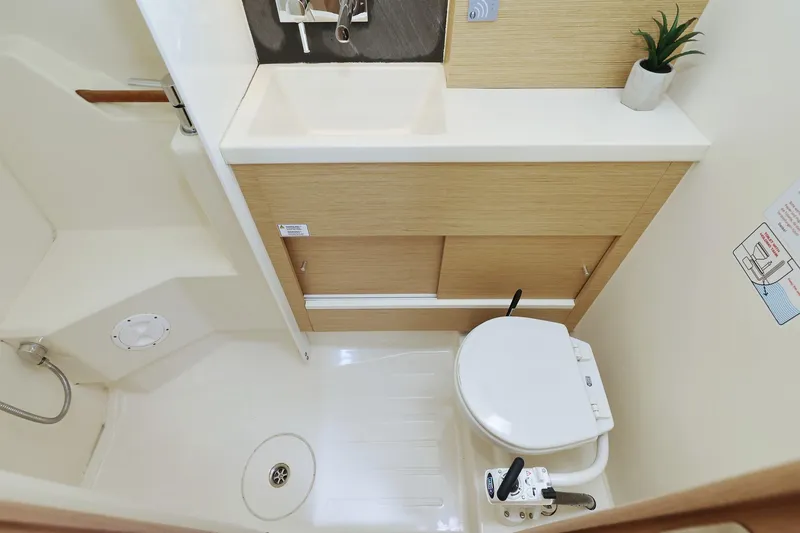 Apollo Yacht Photos Pics 2019 Hanse 458 yacht bathroom with compact toilet, sink, and wooden cabinetry.