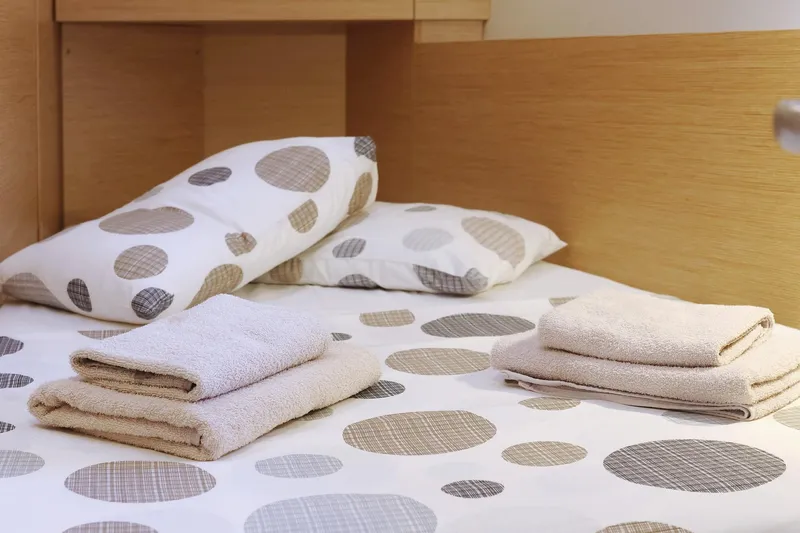 Apollo Yacht Photos Pics Cozy cabin bed with polka dot bedding and neatly folded towels on a Hanse 458 yacht.