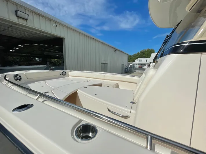  Yacht Photos Pics 2025 Grady-White 281 Coastal Explorer boat deck with seating, docked near a warehouse.