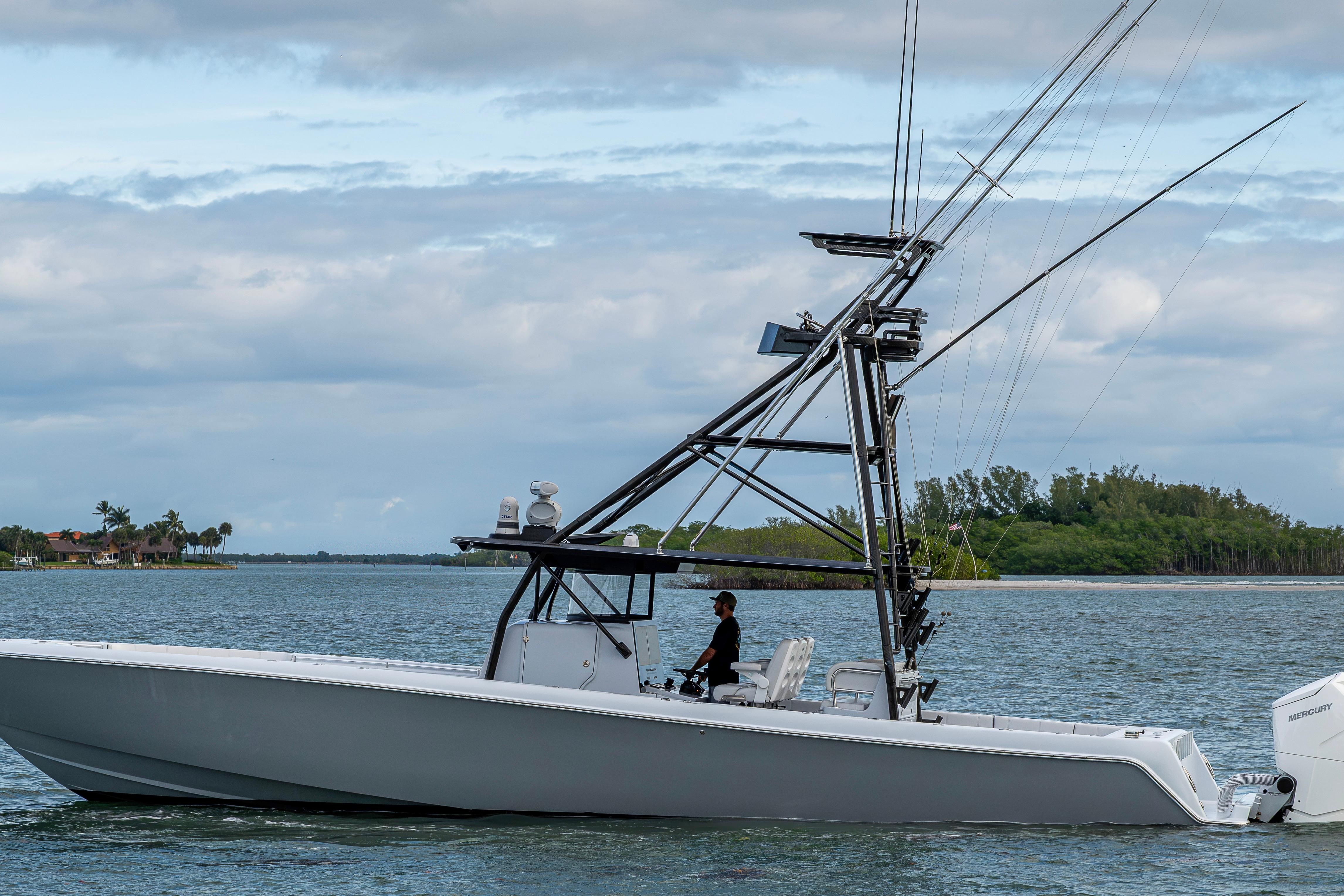 2024 Contender 44 ST boat cruising on a calm waterway with lush greenery.
