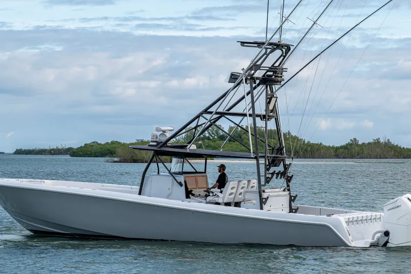  Yacht Photos Pics 2024 Contender 44 ST boat cruising on a calm waterway with lush greenery in the background.