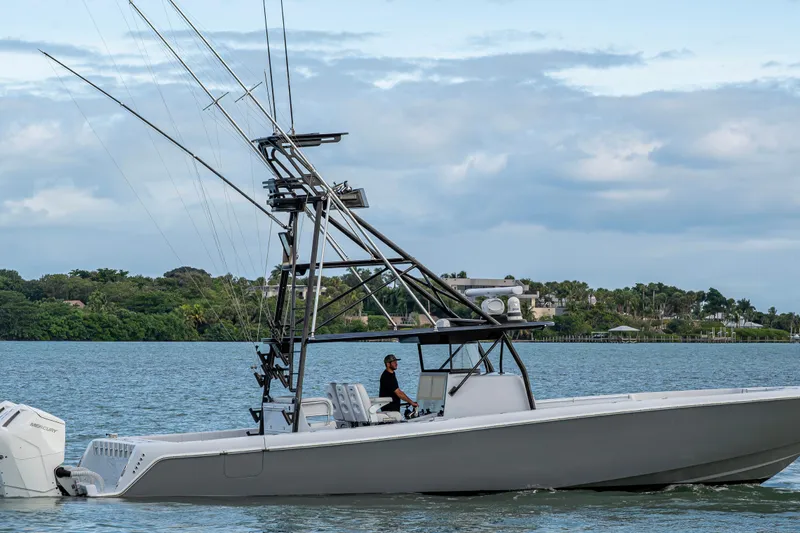  Yacht Photos Pics 2024 Contender 44 ST boat cruising on a scenic waterway with lush greenery.