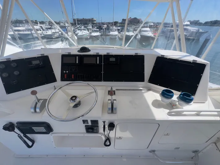 Hear After Yacht Photos Pics Cockpit of a 1995 Bertram 50 Convertible yacht with steering wheel and navigation controls.