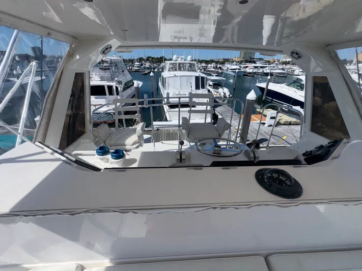 Hear After Yacht Photos Pics Bertram 50 Convertible 1995 yacht helm with marina view, featuring steering wheel and controls.