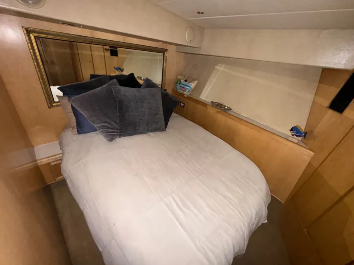 Hear After Yacht Photos Pics Cozy bedroom in 1995 Bertram 50 Convertible yacht with plush pillows and wooden accents.
