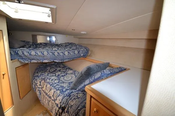 Hear After Yacht Photos Pics 1995 Bertram 50 Convertible cabin with bunk beds and patterned bedding.