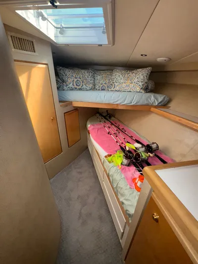 Hear After Yacht Photos Pics Interior of 1995 Bertram 50 Convertible with fishing rods and cozy bedding.