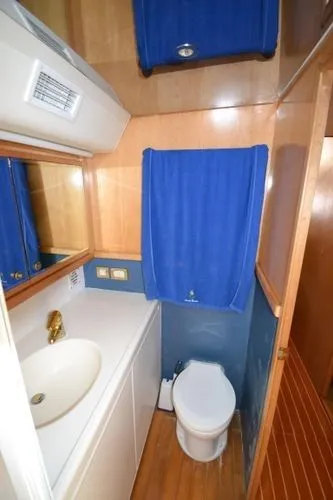 Hear After Yacht Photos Pics 1995 Bertram 50 Convertible yacht bathroom with sink, toilet, and blue accents.